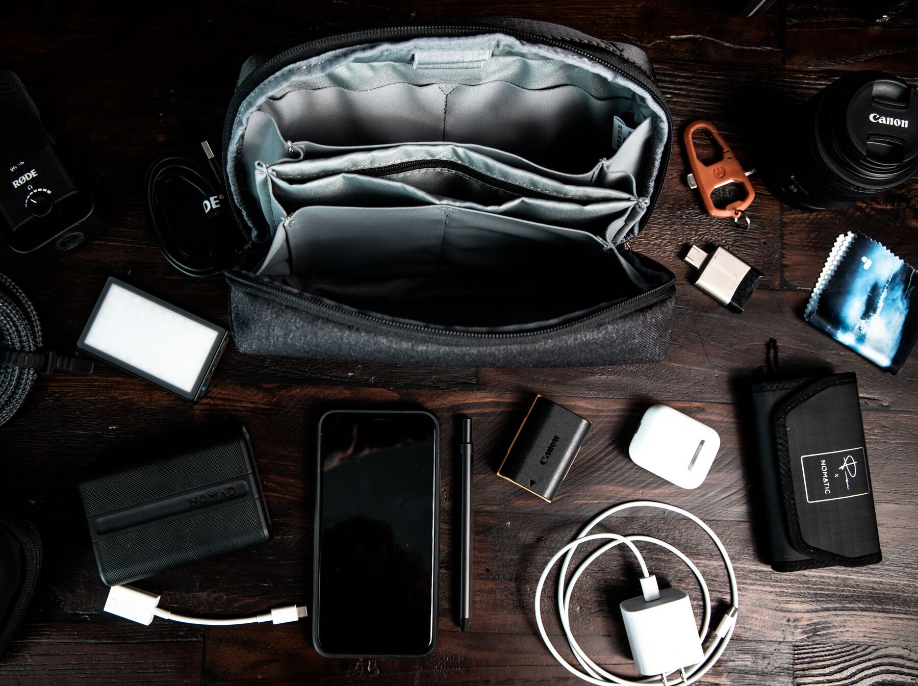 Camera, phone, charging equipment, and portable technology arranged on a dark desk